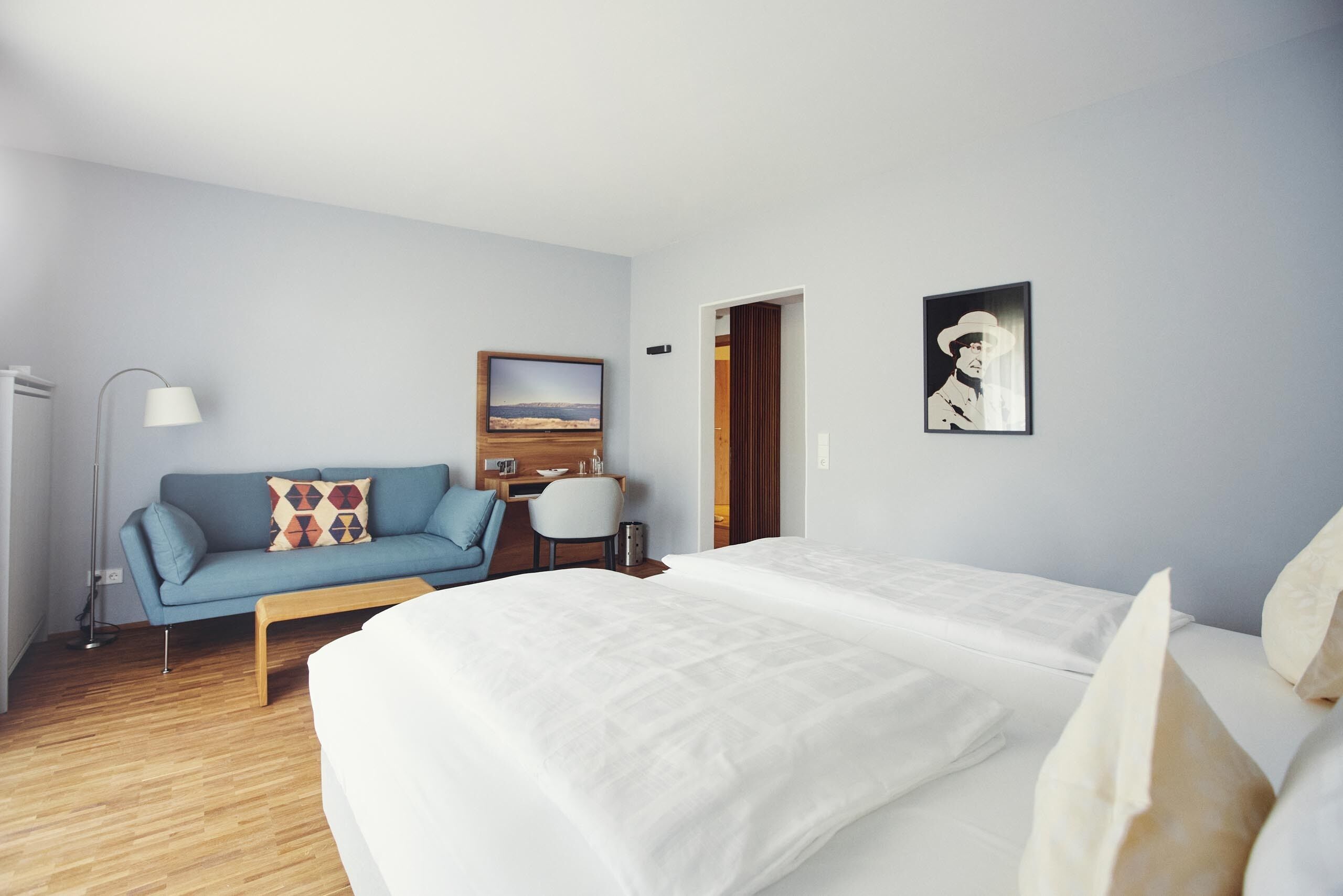 Ein modernes Hotelzimmer mit einem großen Bett, einer Couch, einem Schreibtisch und einem Gemälde an der Wand.