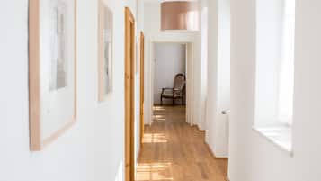 Un pasillo con suelo de madera, paredes blancas y una lámpara colgante.
