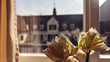 Una ventana con vista a un edificio de estilo arquitectónico particular, que incluye una torre y múltiples ventanales.
