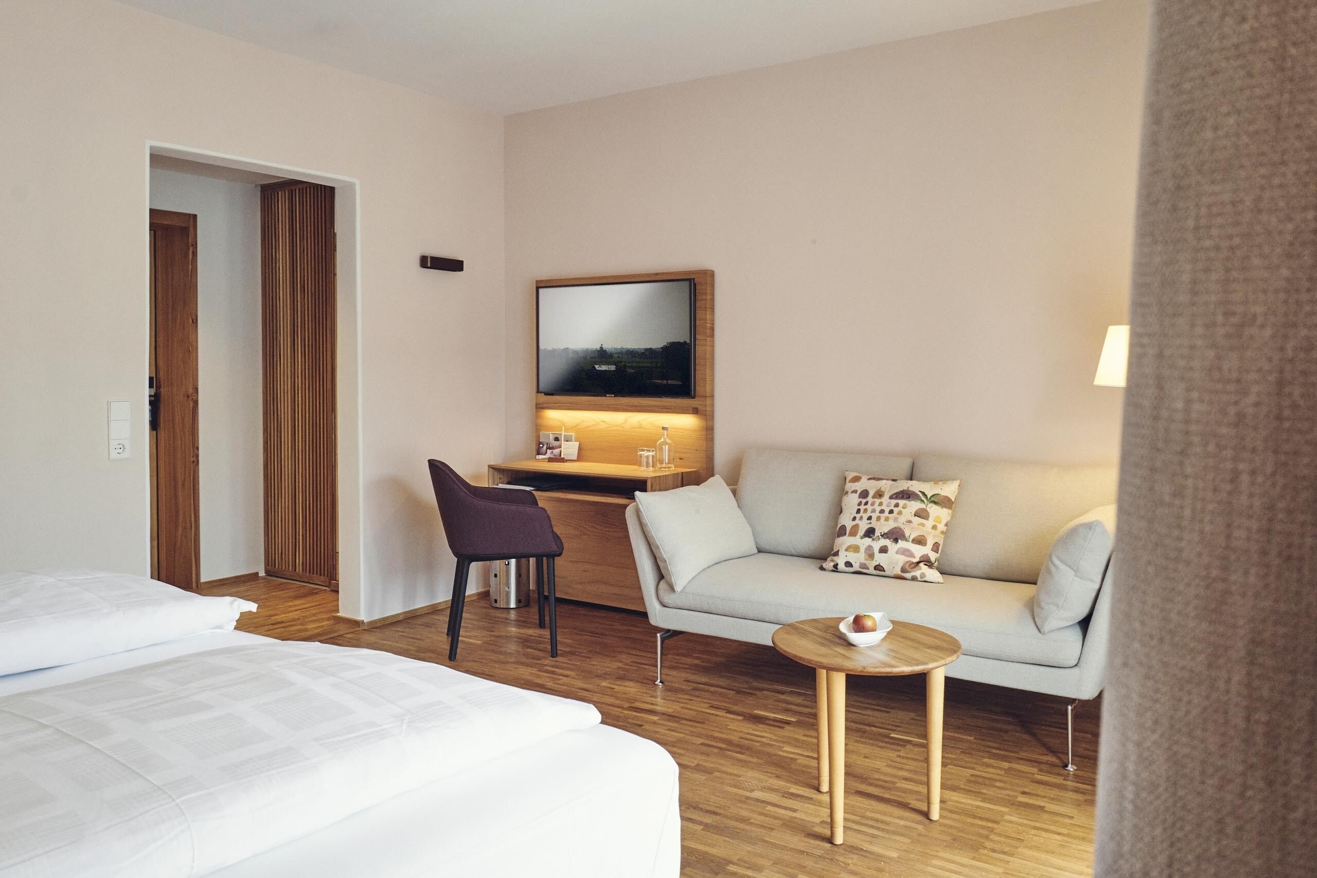 Een hotelkamer met een bed, een bank, een klein tafeltje, een bureau en een televisie.