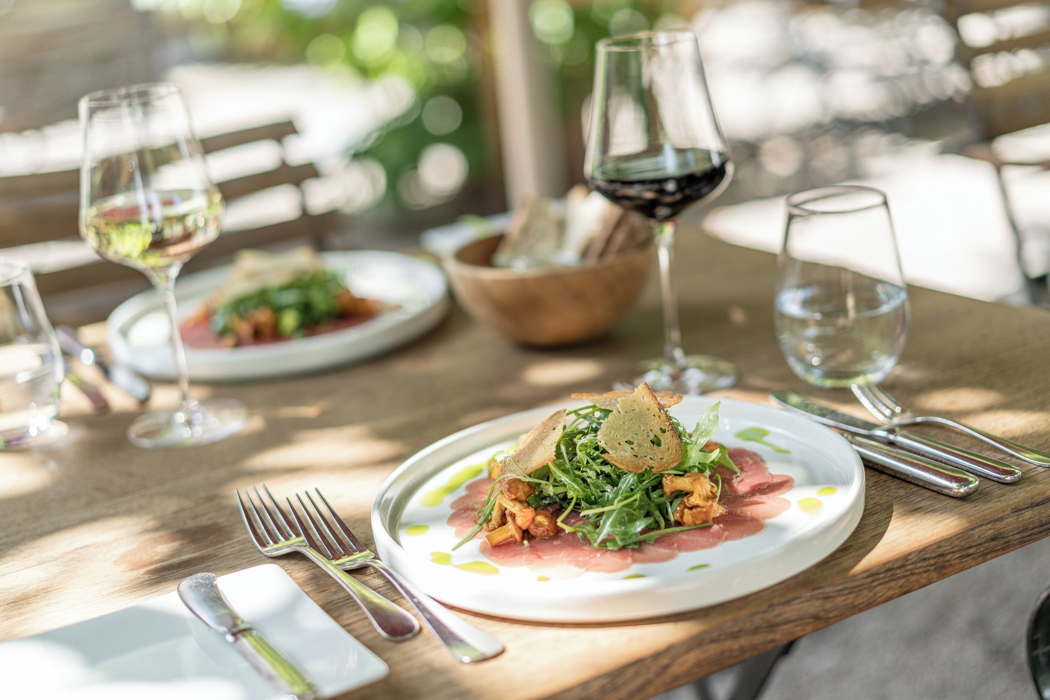Une table à manger avec des assiettes remplies de nourriture, des verres à vin et des couverts.