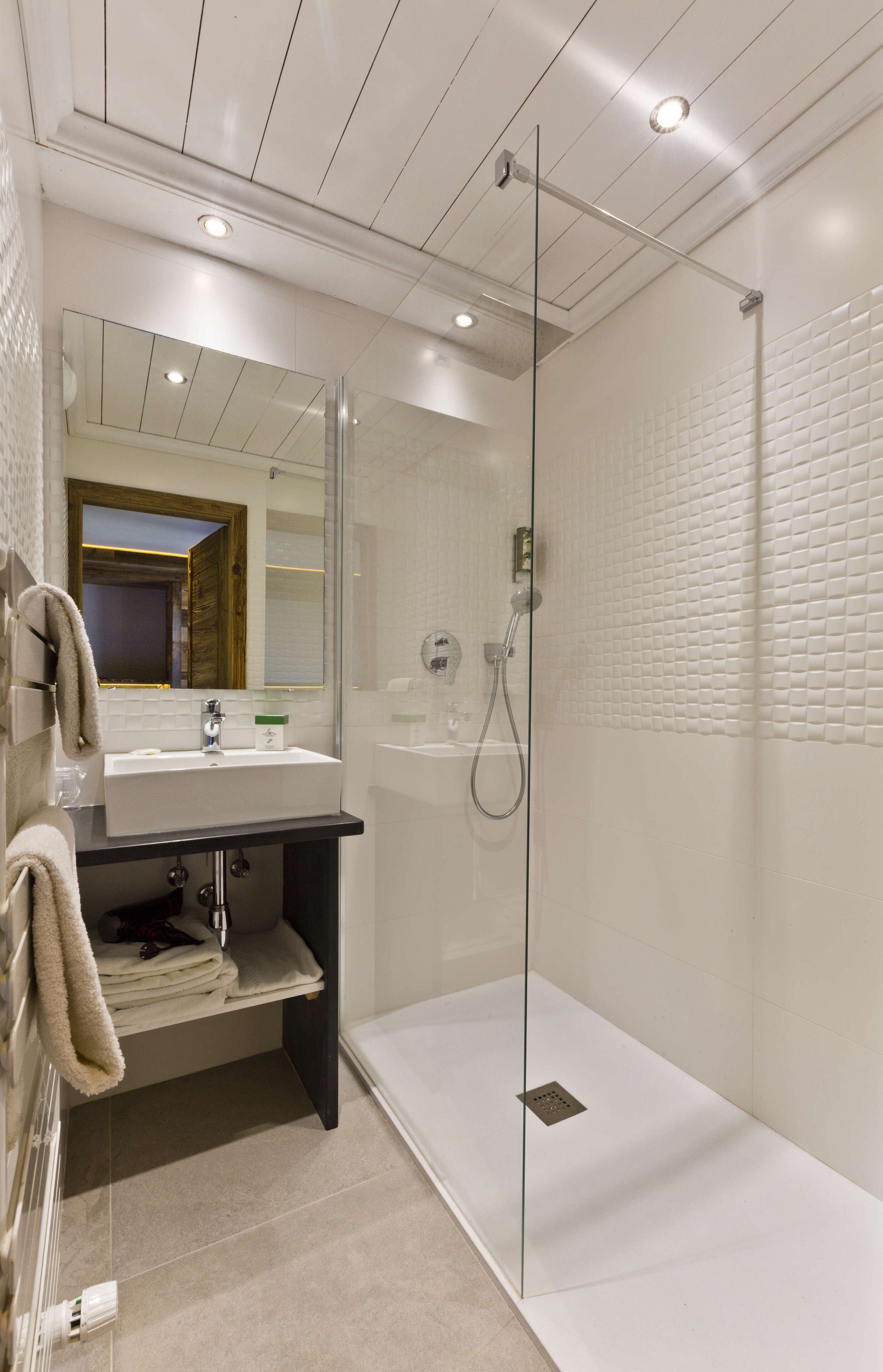 A modern bathroom with a glass-enclosed shower, a vanity with a sink, and a mirror.