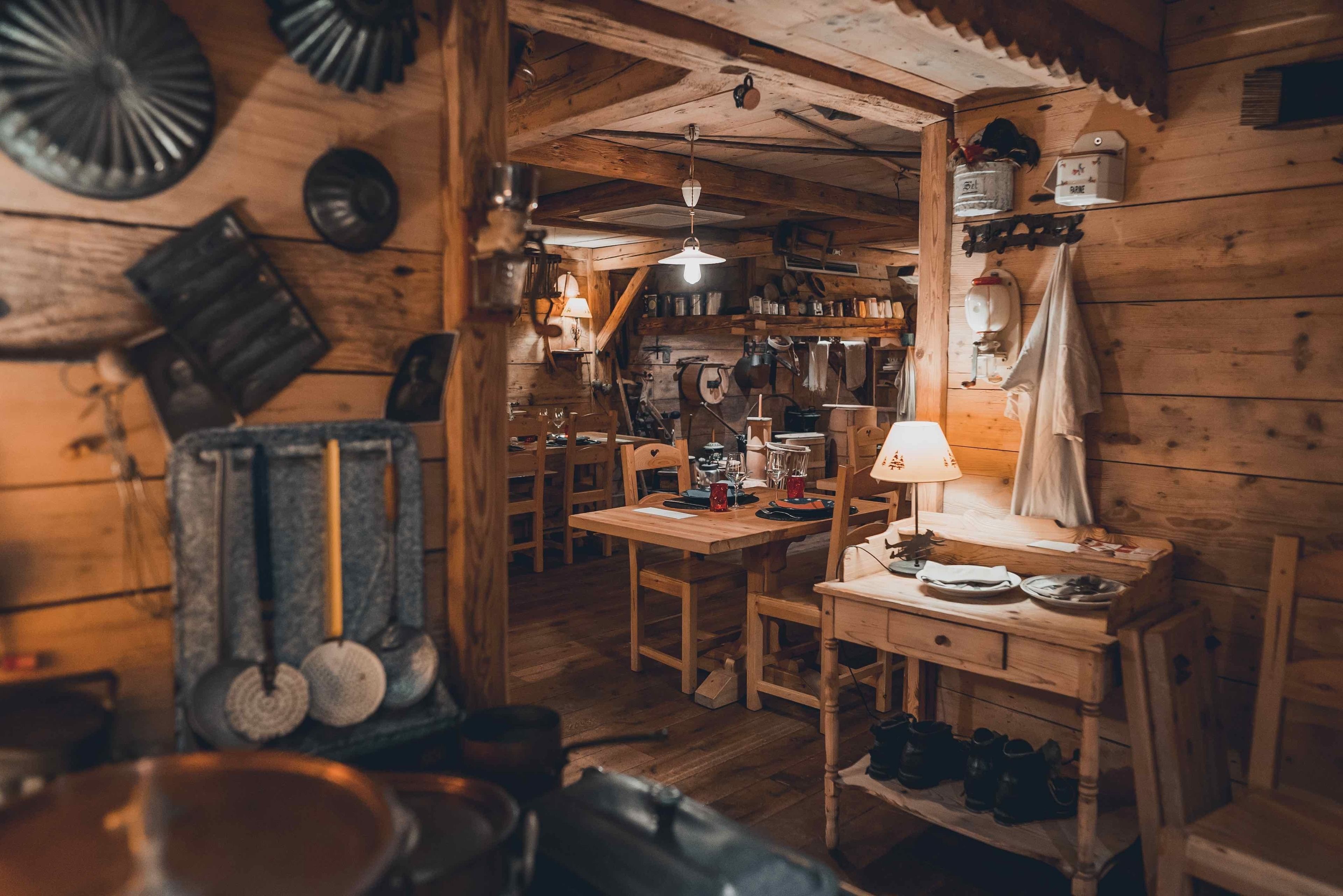 Un interior rústico de madera con una mesa, sillas y diversos utensilios de cocina.