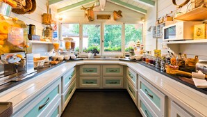 A kitchen with a large island, white cabinets, and a view of greenery outside. - Chalet-Hôtel Les Gentianettes, The Originals Relais (Hôtels-Chalets de Tradition) (La Chapelle-d'Abondance)