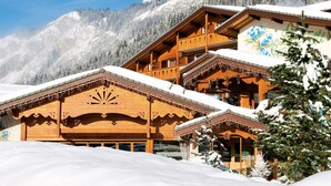 A wooden chalet with a balcony, surrounded by snow-covered mountains and trees. - Chalet-Hôtel Les Gentianettes, The Originals Relais (Hôtels-Chalets de Tradition) (La Chapelle-d'Abondance)