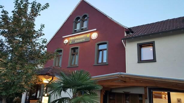 Un bâtiment portant une enseigne indiquant qu’il s’agit d’un hôtel et d’un restaurant appelé « Exquisitely ».