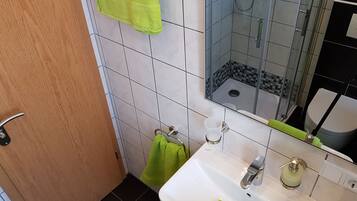 A bathroom with a white sink, a mirror, a shower, and a toilet.