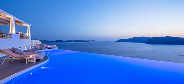 A infinity pool with lounge chairs and a view of the sea.