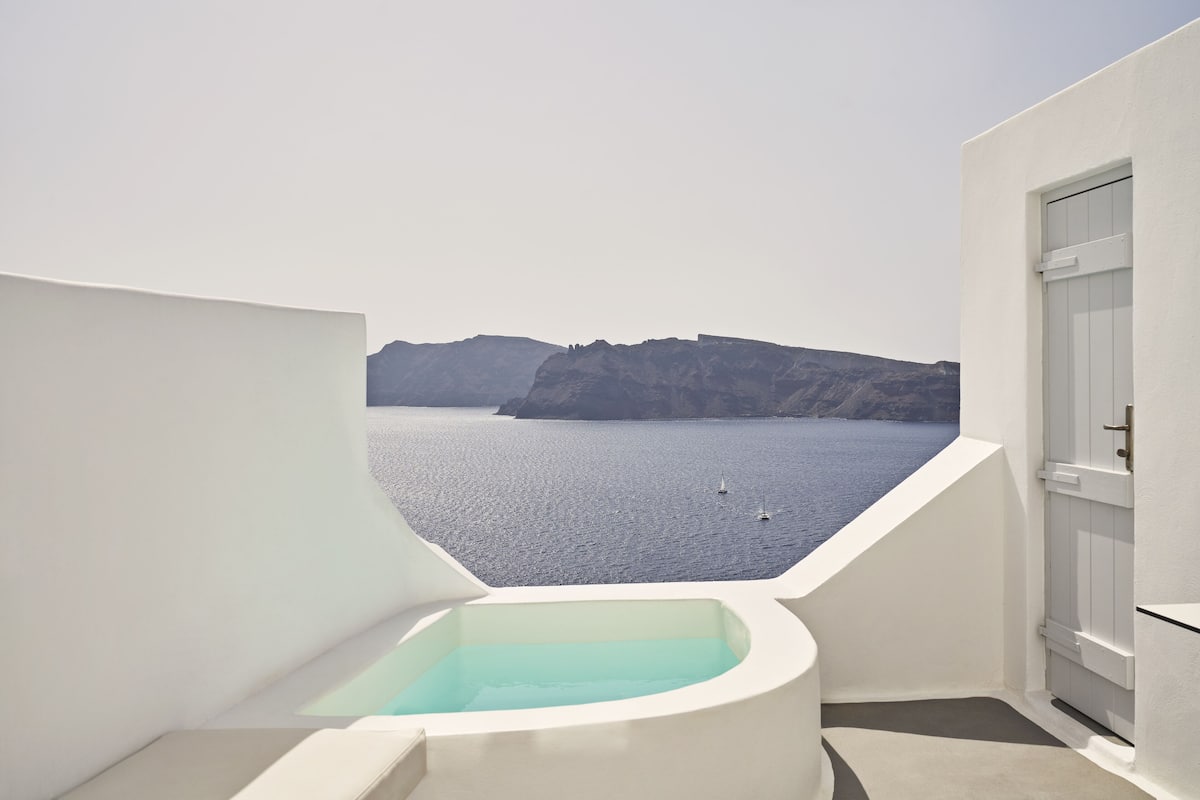 A modern bathroom with a bathtub and a view of the sea and cliffs.