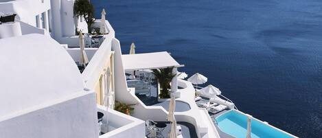 A white building with a pool and a view of the sea.
