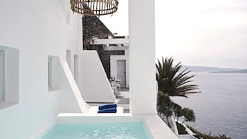Un espace piscine extérieur moderne avec vue sur la mer, des murs blancs et un luminaire suspendu au plafond en osier.