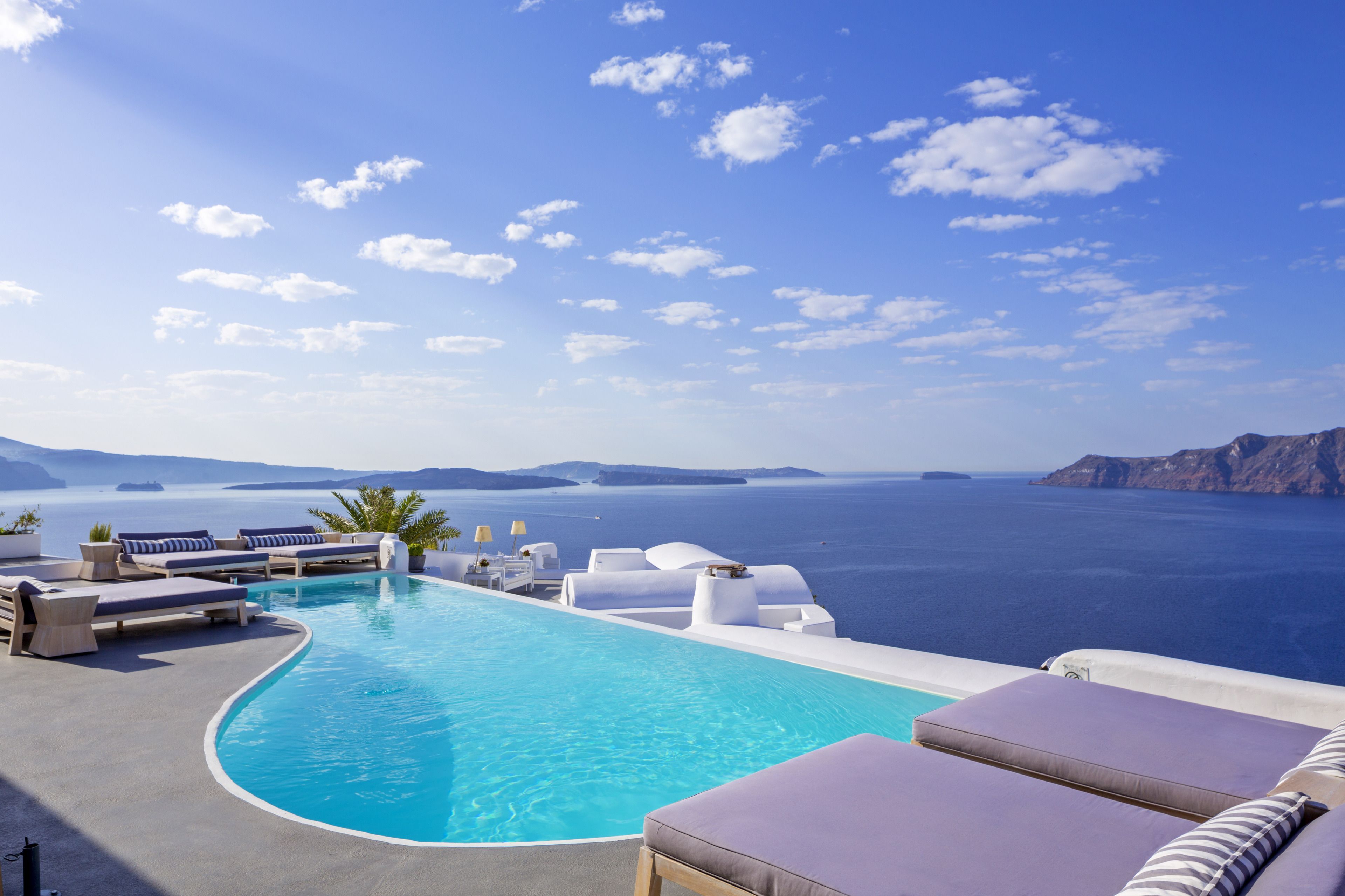 An infinity pool with white lounge chairs and a view of the sea.