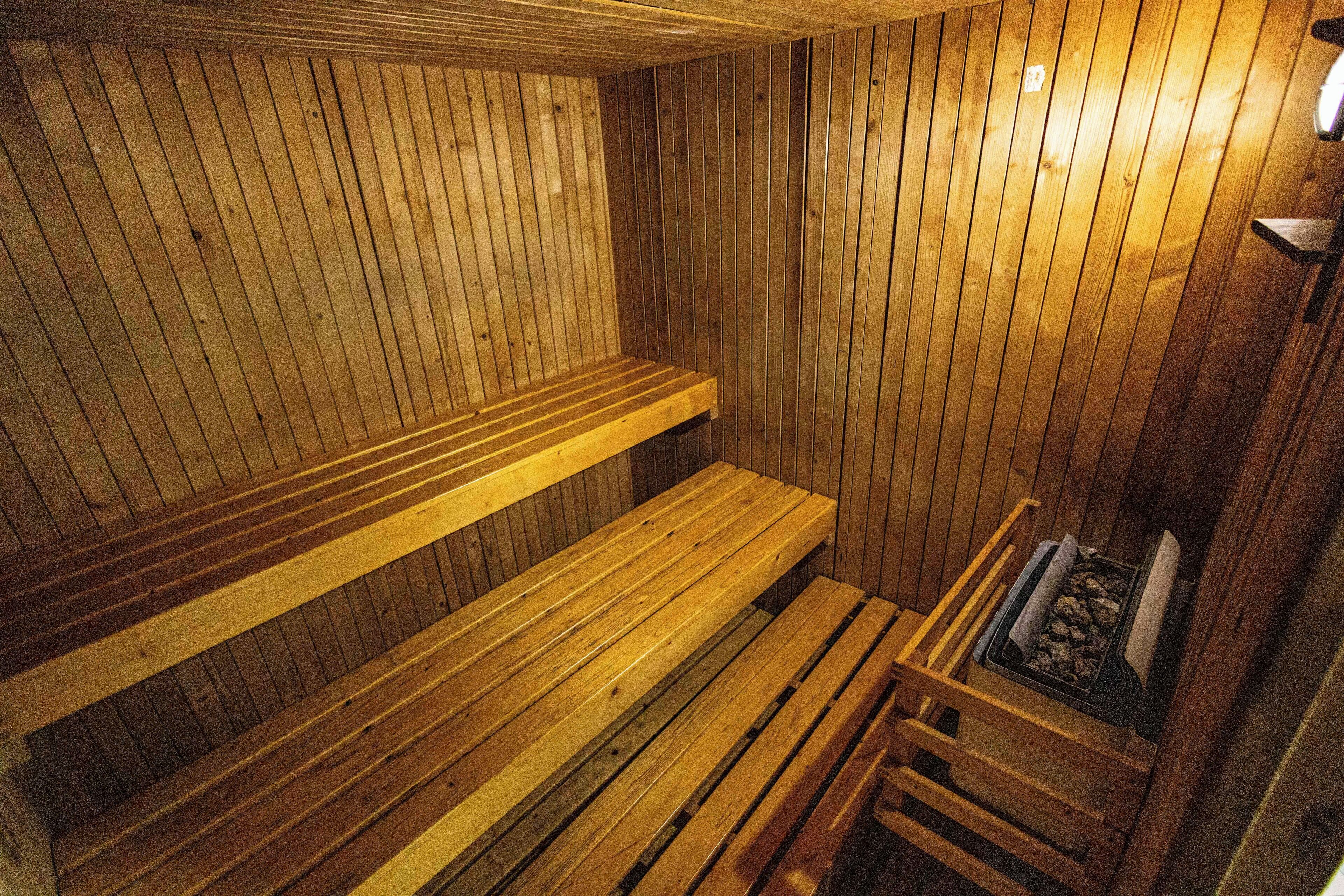 Una sauna con bancos de madera y un banco con una bandeja de piedras.