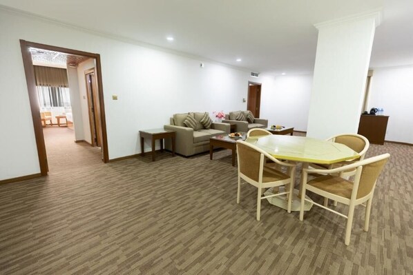 A spacious living room with a dining area, a sofa set, and a small table with chairs. - Hamdan Plaza Hotel (Salalah)