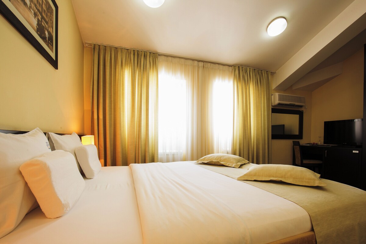 A hotel room with a large bed, a desk, and a television.