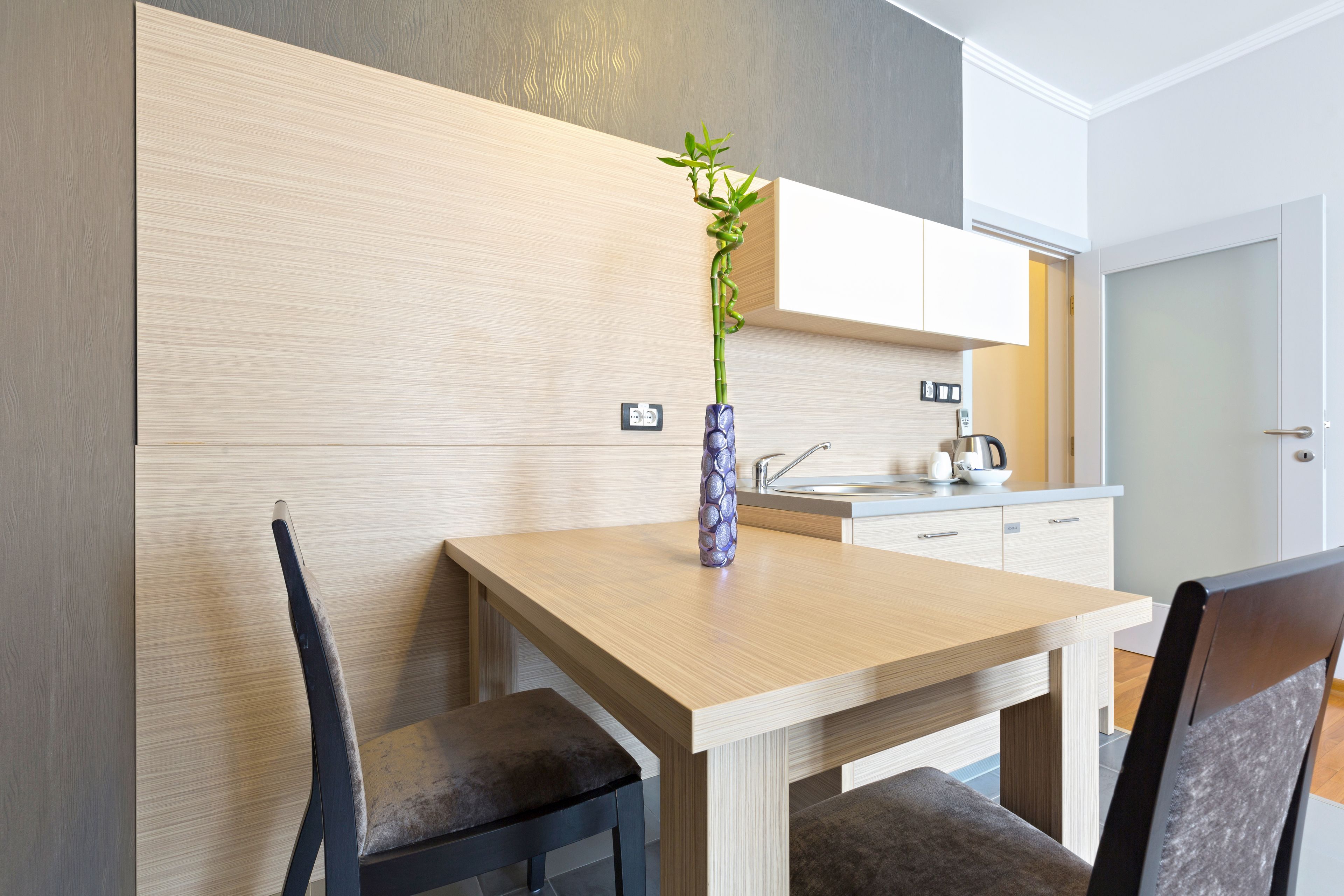 Una cocina moderna con una mesa de madera, dos sillas y una planta decorativa en un florero.