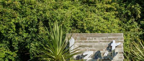 A sign for a restaurant bar hotel with a stone facade and surrounding greenery.