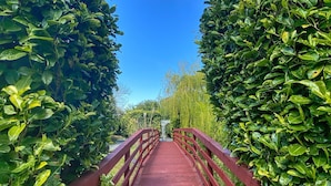 A red metal bridge with railings, surrounded by dense green foliage. - Lazaat Hotel (Cottingham)