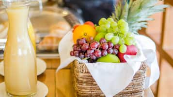 Un desayuno con una cesta de frutas, un jarro de jugo y una bandeja de pasteles.