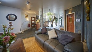 A modern interior with a leather sofa, a round mirror, and a staircase leading to an outdoor area. - Lazaat Hotel (Cottingham)