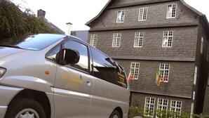 Een zilveren auto geparkeerd voor een gebouw met veel ramen en een vlag.