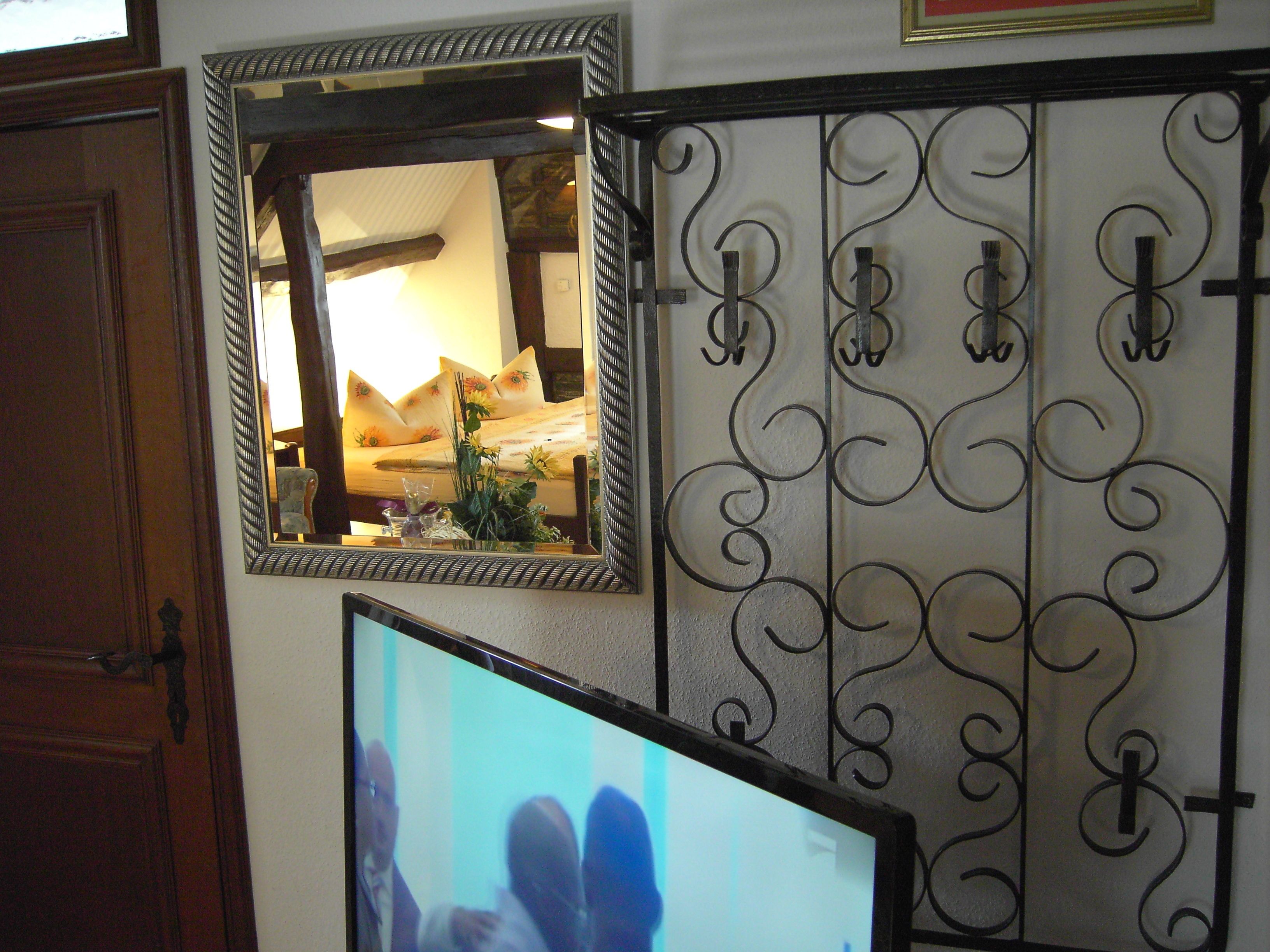 A room with a bed, a mirror, and a decorative metal gate.