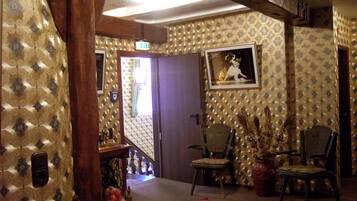A room with patterned wallpaper, a framed picture on the wall, and several chairs.