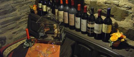 Un rincón de bar con un fondo de pared de piedra, varias botellas de vino y una jaula decorativa.
