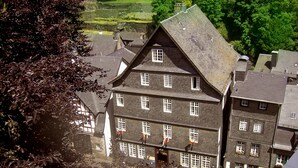 Een traditioneel meerlaags gebouw met een steile kap, meerdere ramen en een duidelijke ingang.