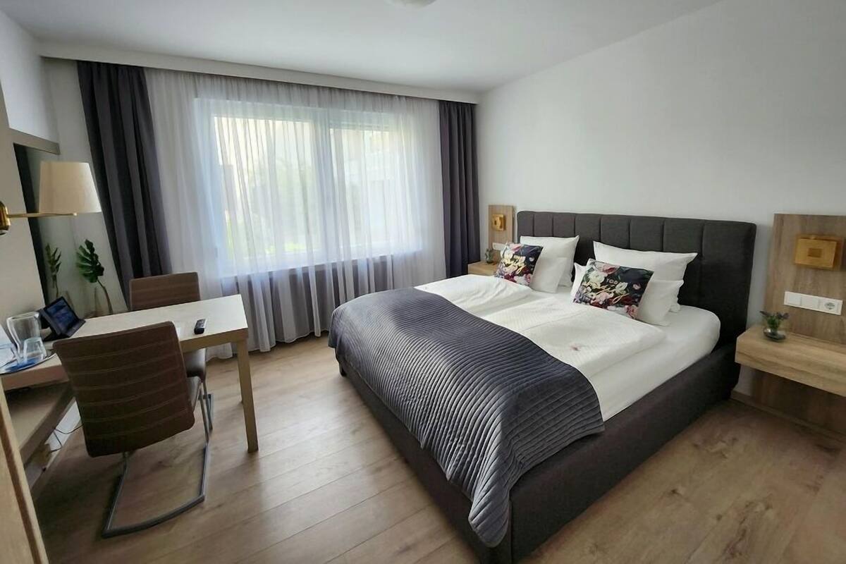 A modern hotel room with a large bed, a desk, and a chair.