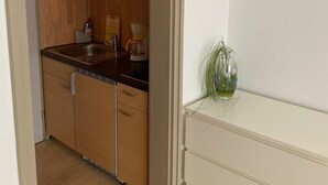 A compact kitchen with wooden cabinets, a sink, and a countertop. - Stadthotel Geis (Bad Neustadt an der Saale)