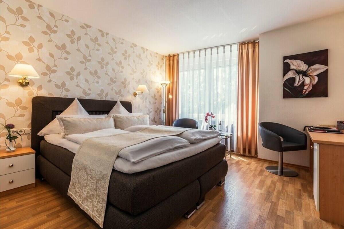 A modern hotel room with a large bed, a desk, and a chair.