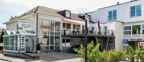 A hotel with a glass facade, outdoor seating, and a parking sign.