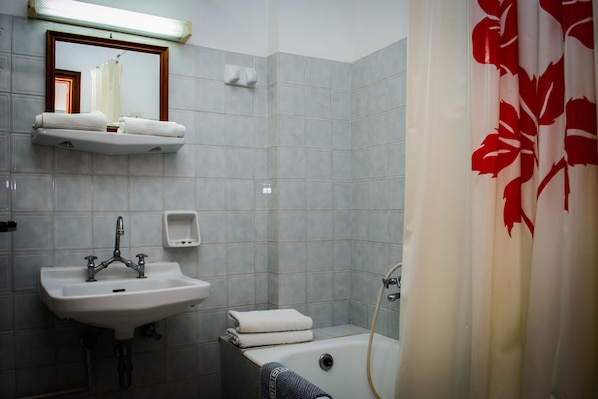A bathroom with a sink, mirror, towel rack, and bathtub.