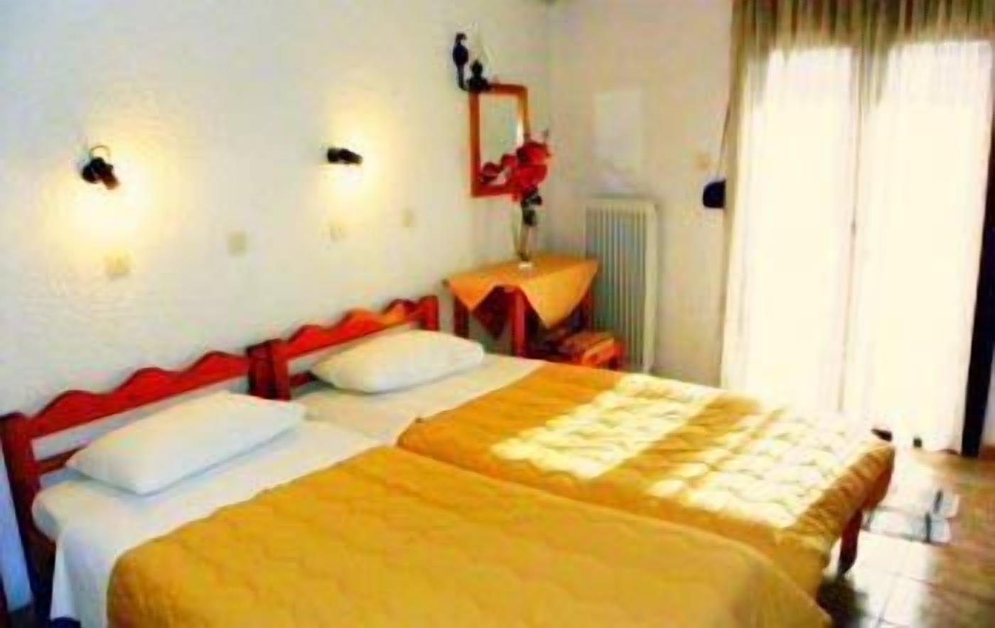 A double bed with a yellow bedspread, a nightstand with a mirror, and a radiator on the wall.