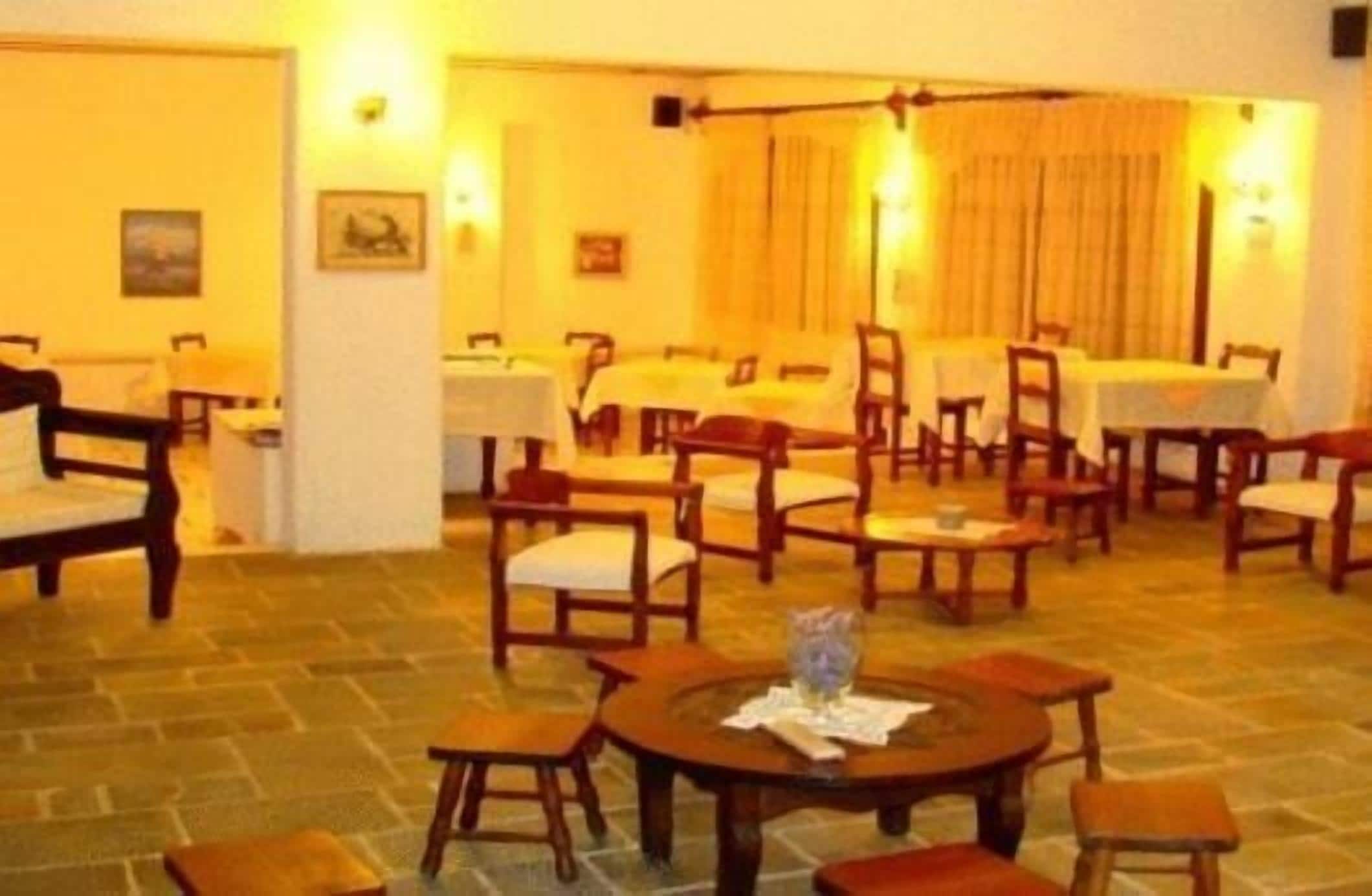 A hotel lobby with multiple seating areas, including round tables and chairs, and a dining area with tables and chairs.