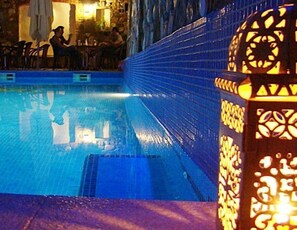 A swimming pool with a tiled edge and a decorative pillar with a geometric pattern.