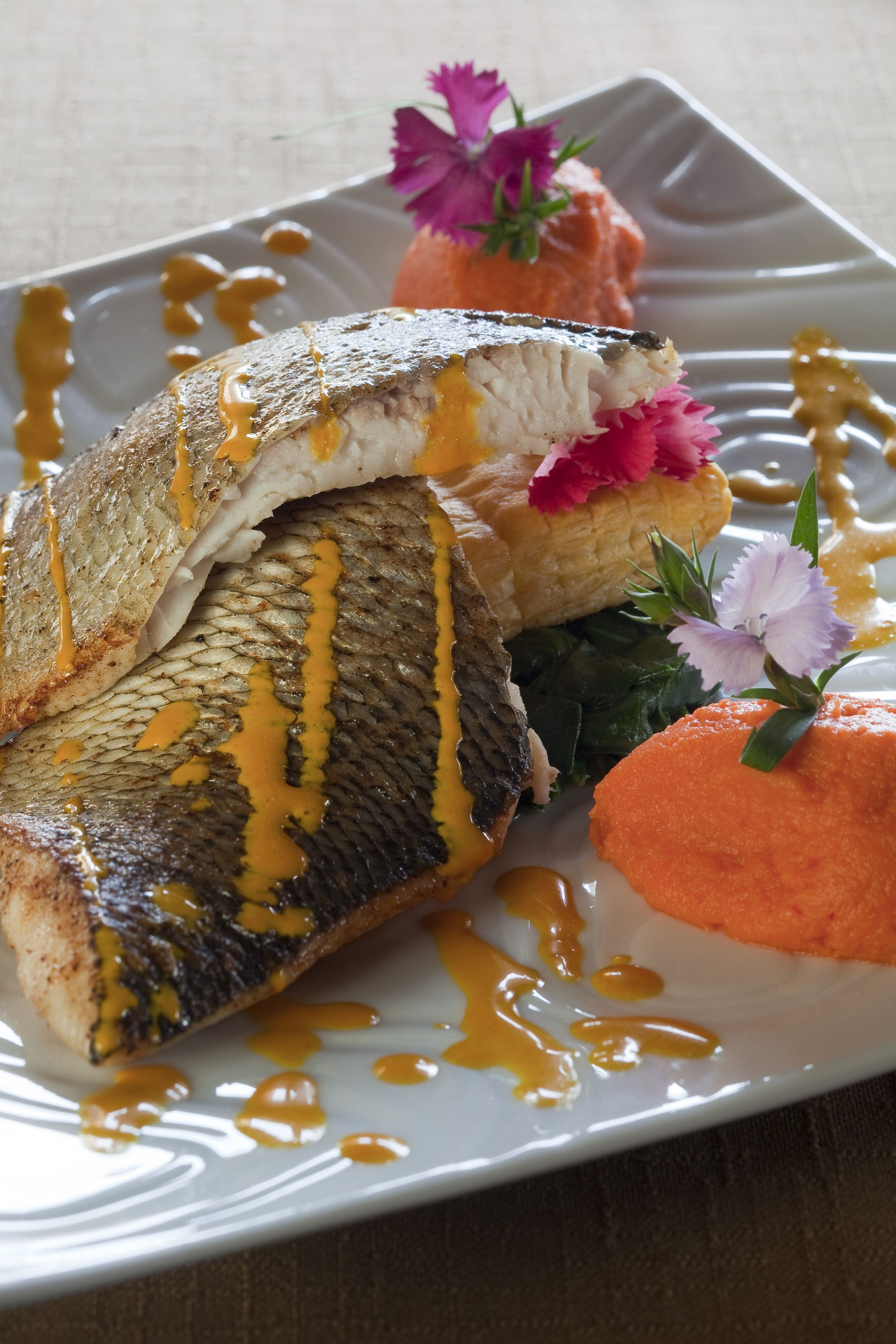 Un piatto con pesce, salsa e guarnizioni.