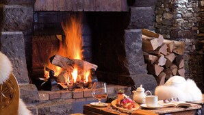 A cozy fireplace with a wooden mantel, a heart-shaped decoration, and a stack of firewood. - Le Sherpa (Les Belleville)