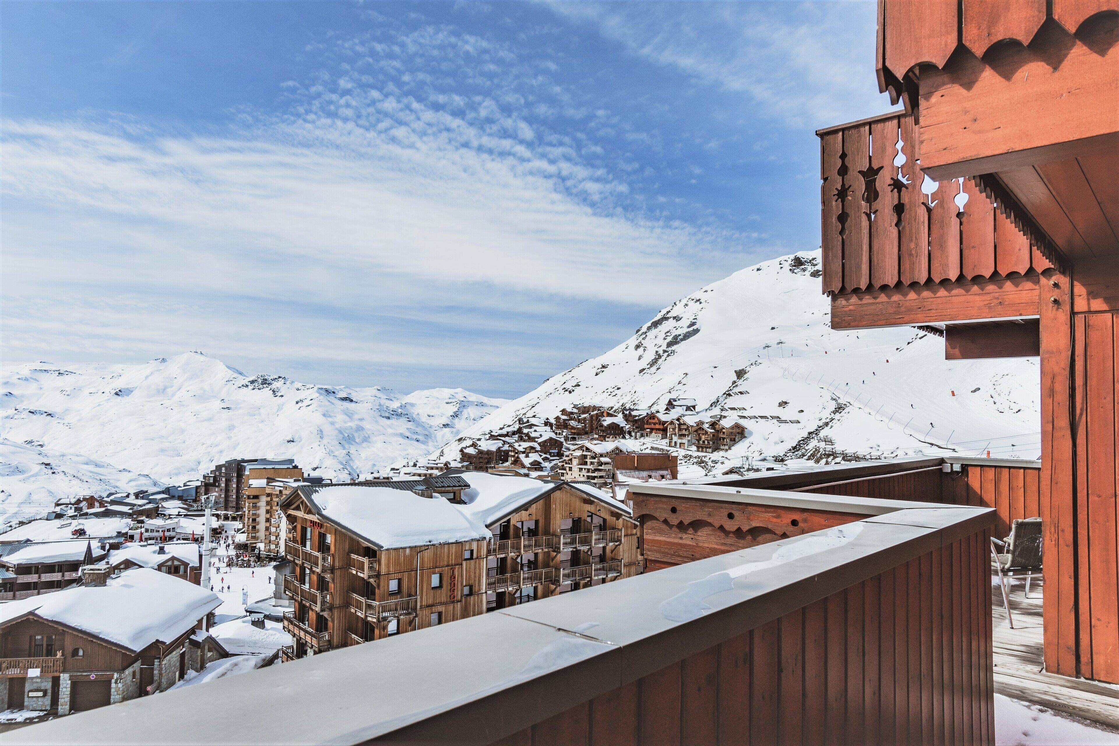 A snow-covered mountain town with wooden buildings and a wooden balcony.