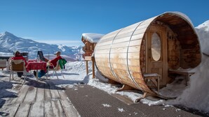 A wooden cabin with a curved roof, a wooden door, and a bench outside. - Le Sherpa (Les Belleville)