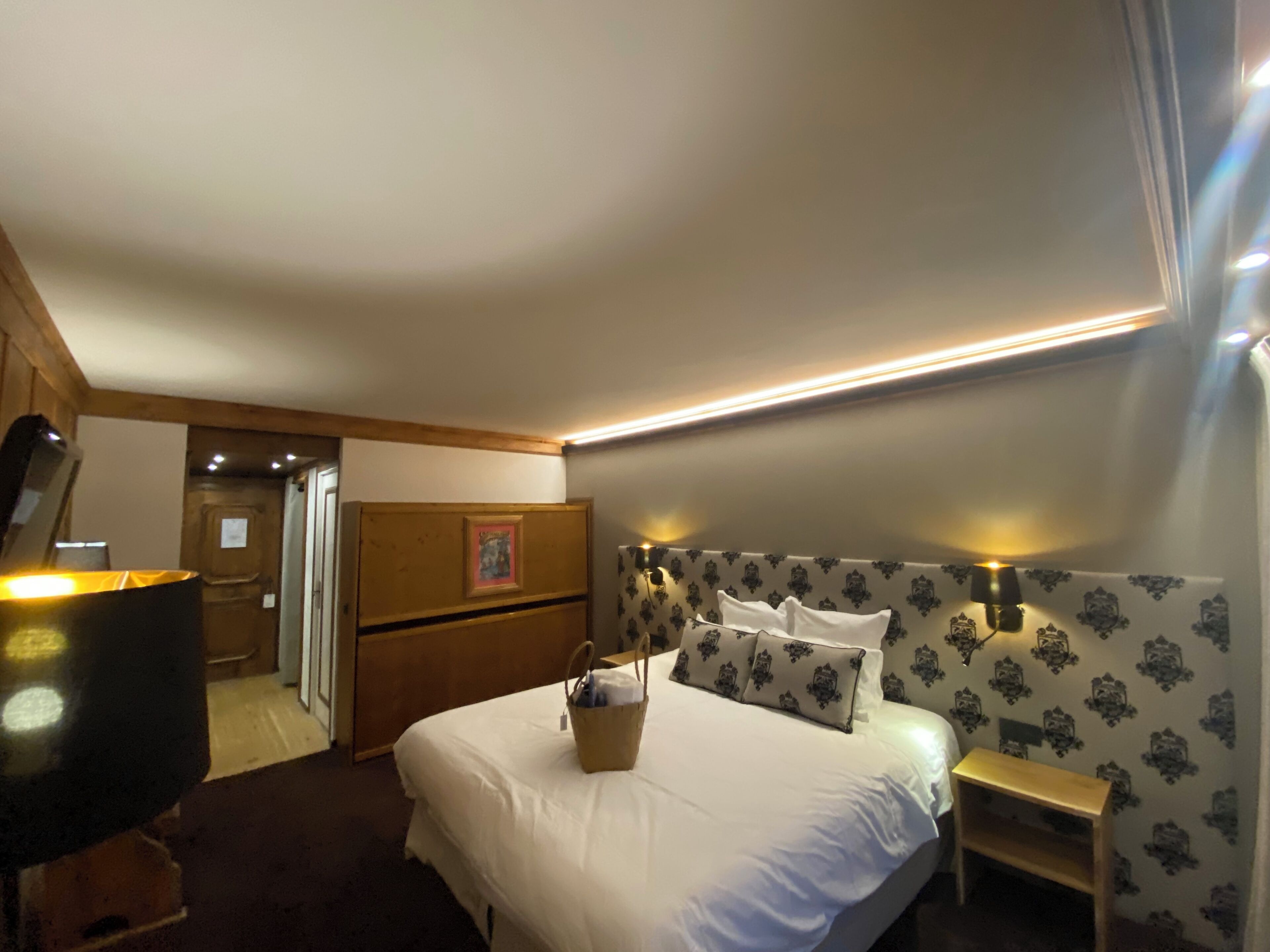 Une chambre d’hôtel comprenant un lit, des tables de chevet, une commode, un meuble à tiroirs et un téléviseur.