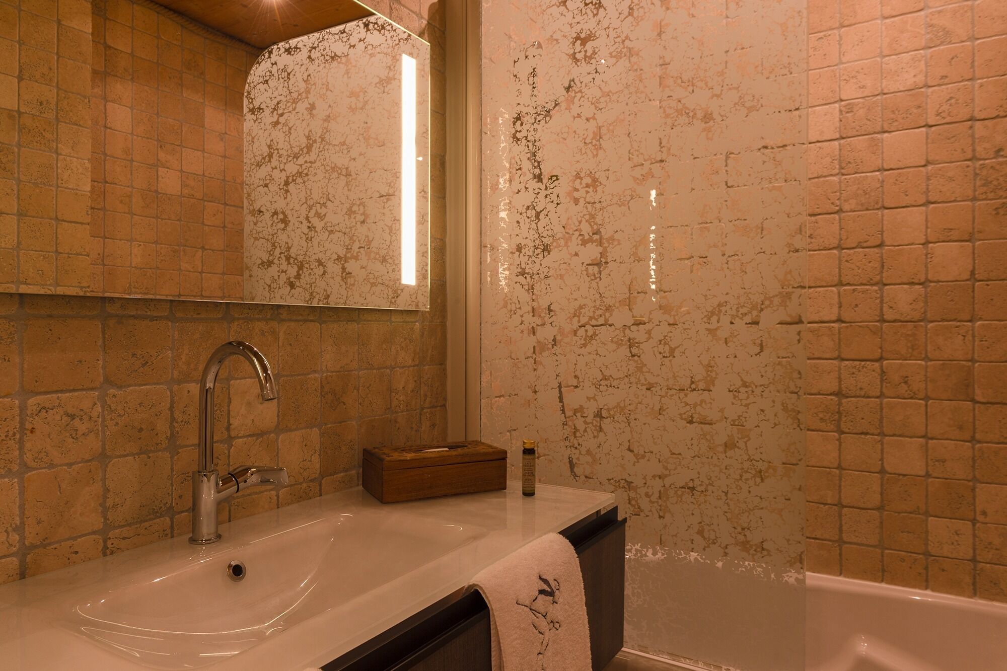A bathroom with a sink, mirror, and bathtub.