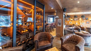 A cozy interior with leather armchairs, a wine rack, and a wooden ceiling. - Hôtel Macchi Restaurant & Spa (Chatel)