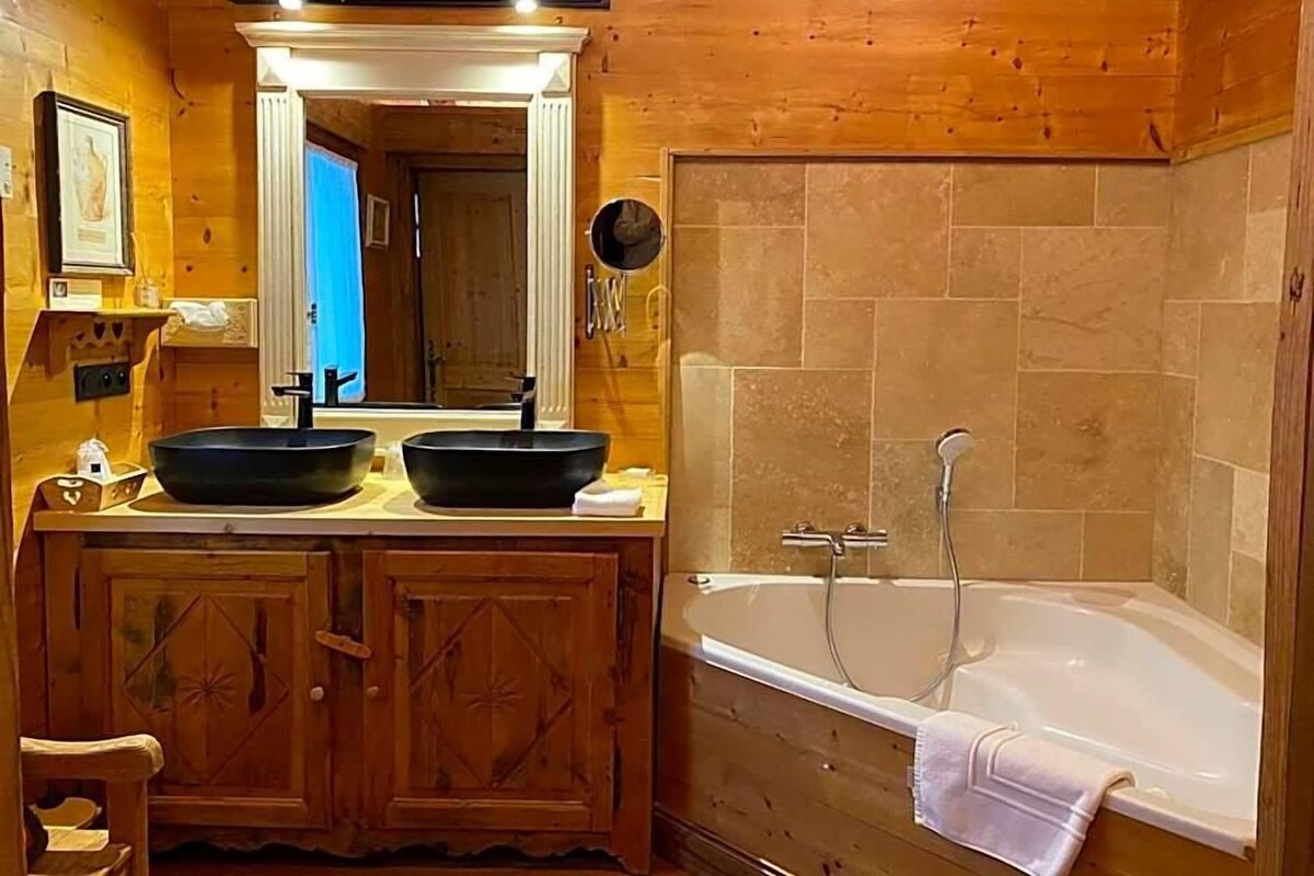 Ein Badezimmer einer Holzhütte mit zwei Waschbecken, einer Badewanne und einem Spiegel über dem Waschtisch.
