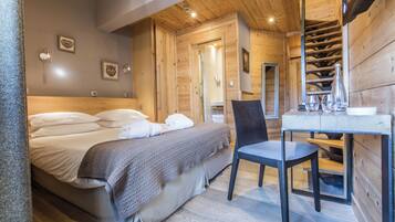 A wooden cabin bedroom with a bed, chair, and a small table with glasses.