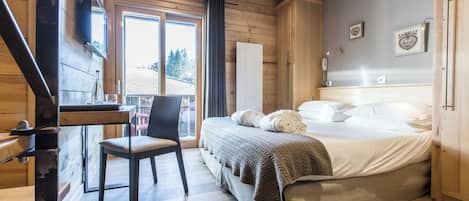 Un interior de madera con una cama, una silla, un escritorio y un ventanal.