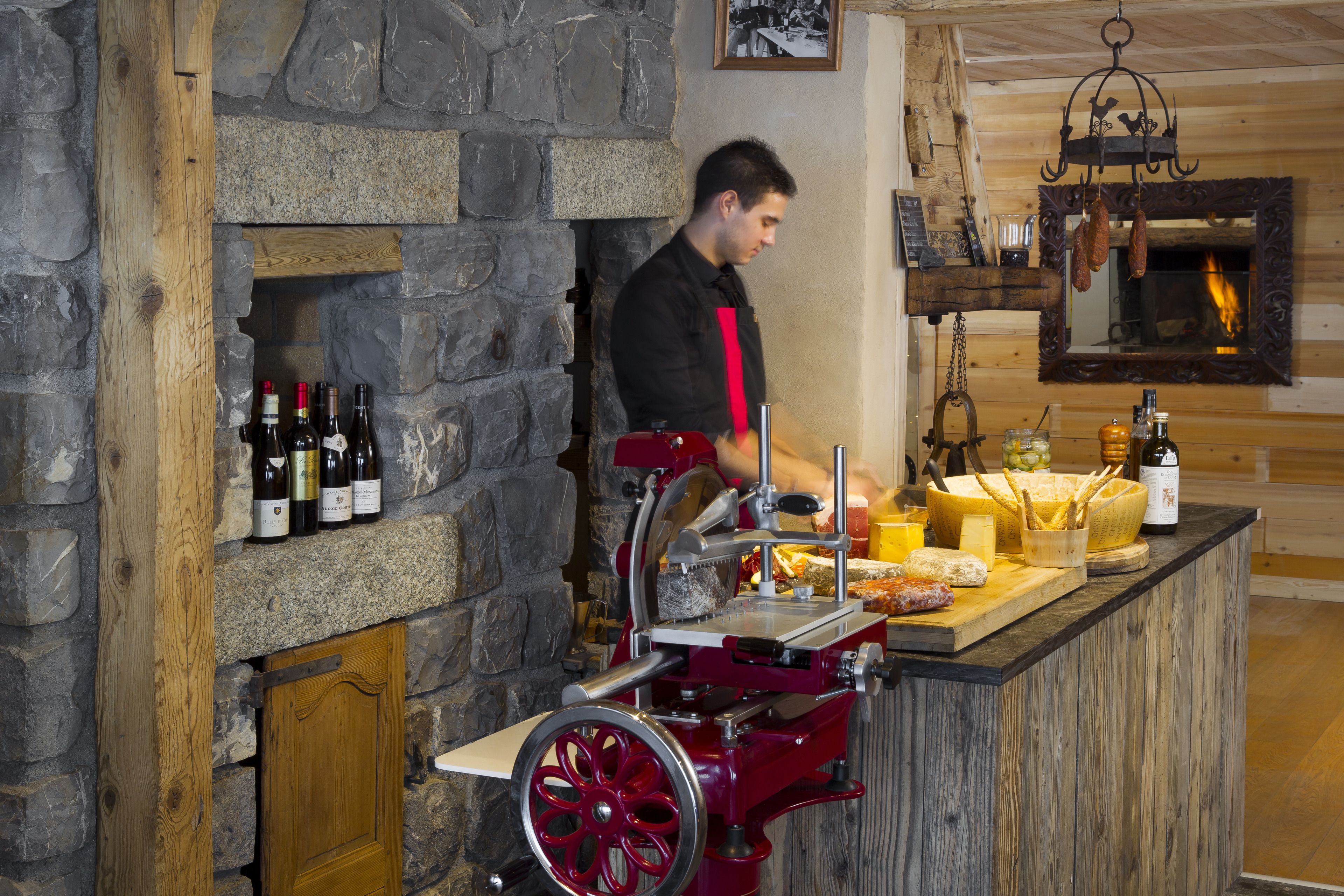 A rustic bar area with a stone wall, wooden beams, and a variety of food and drink items displayed.
