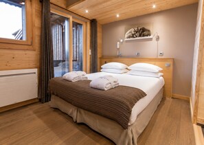 Ein Zimmer mit Holzwänden, einem Bett, einem Fenster mit Vorhängen und einer Wandleuchte.