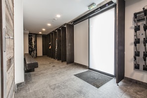 Un couloir avec un banc, une porte et une caméra de surveillance fixée au mur.